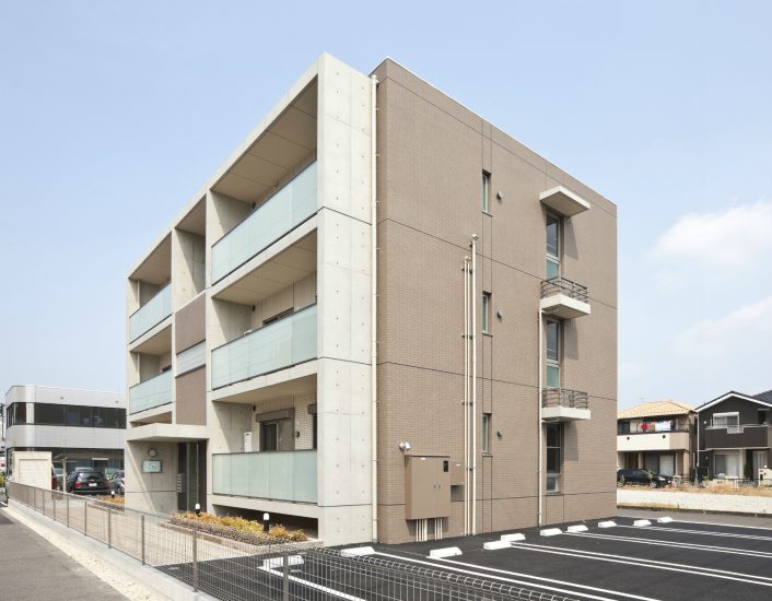 愛知県一宮市の全室角部屋の賃貸マンションの建物前に植栽があり横に駐車場