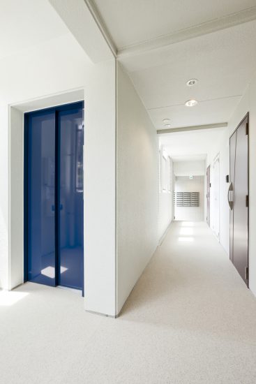 名古屋市千種区の賃貸マンションの通路とおしゃれな青色のエレベーター扉