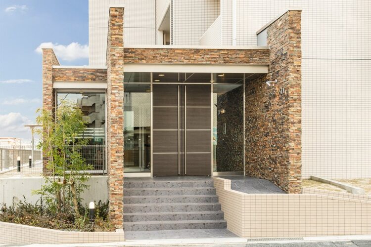 名古屋市名東区の賃貸マンションの凹凸のある石壁と植栽のあるエントランス