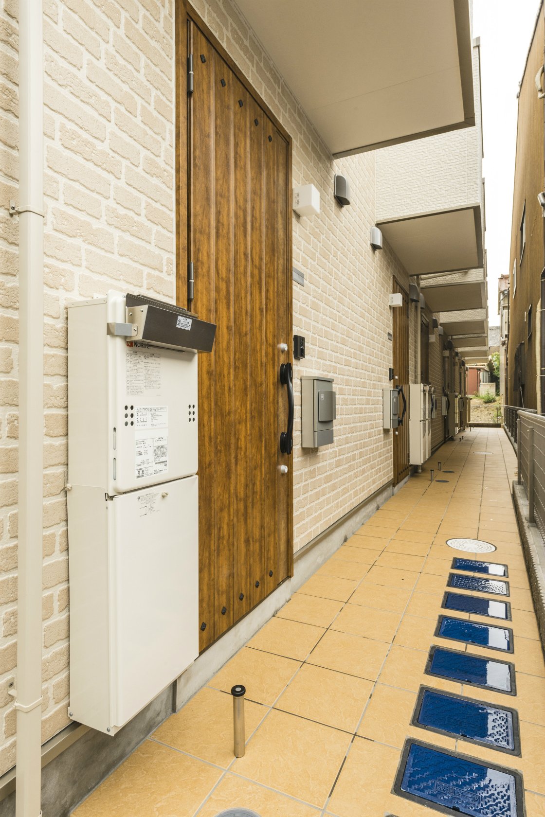 名古屋市緑区のロフト付きメゾネット賃貸の木の玄関ドアがおしゃれな通路