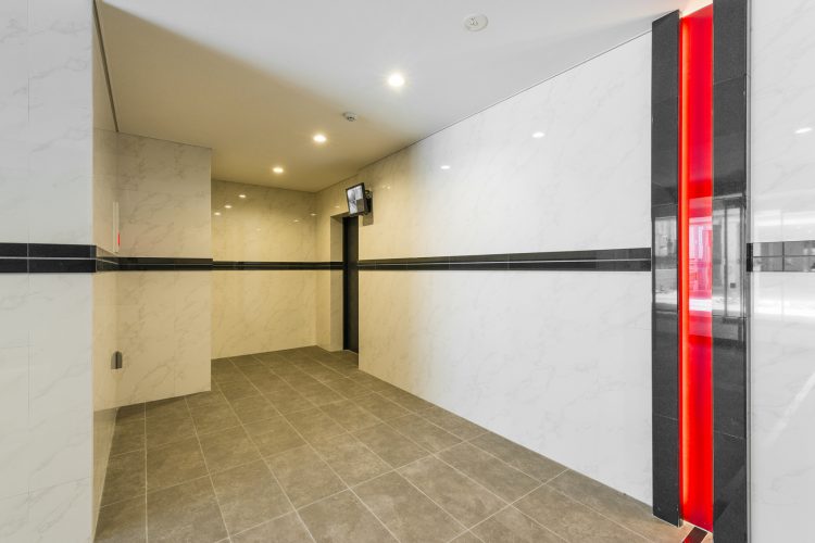 名古屋市千種区の賃貸マンションの赤いラインが目を引くデザインのエレベーターホール