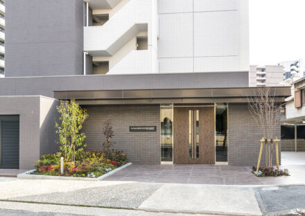 約2000平米の土地のモダンな賃貸マンションの植栽のあるエントランス