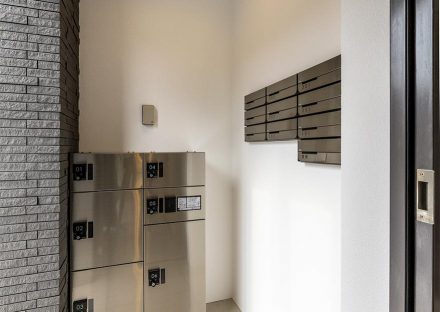 名古屋市名東区の3階建て賃貸マンションのメタリックな宅配ボックスとメールボックス