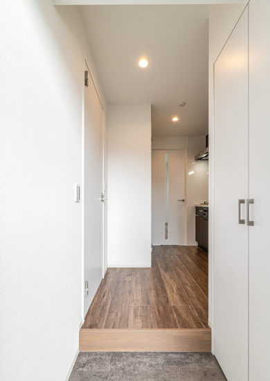 名古屋市東区の11階建てワンルームマンションの木目調の床とキッチンパネルがおしゃれな玄関