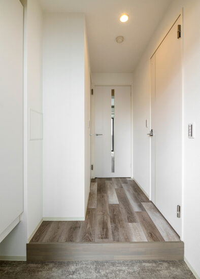 名古屋市東区の高級感のある9階建てワンルーム賃貸マンションの木目調のフローリングと白い壁と建具のシンプルな玄関