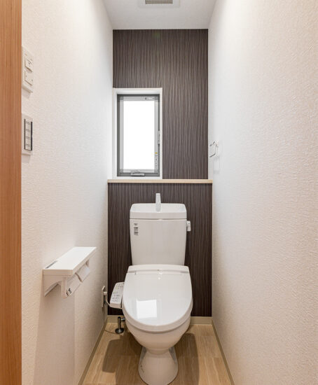 愛知県刈谷市のおしゃれな外観のナチュラルテイストな戸建賃貸住宅の棚付きの窓がある明るいトイレ