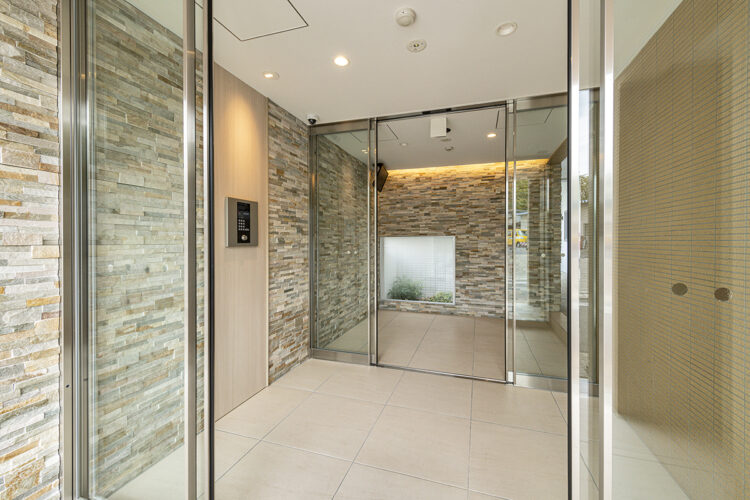 名古屋市名東区のナチュラルなデザインの3階建て賃貸マンションの透明感のある扉の明るいオートロック付きの風除室