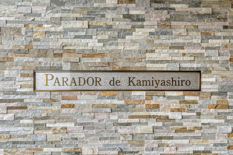 名古屋市名東区のナチュラルなデザインの3階建て賃貸マンションの凹凸のある様々な色のタイルの壁に高級感のある館銘板