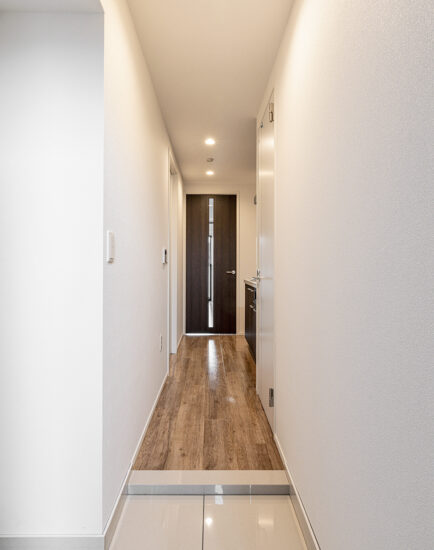 名古屋市昭和区の12階建て高級感ある賃貸マンションのダークブランのドアと木目調の床の玄関