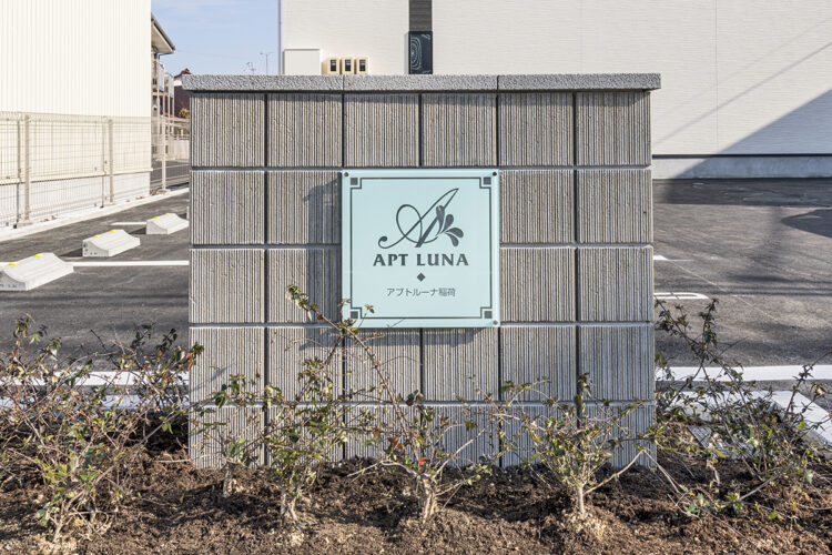 愛知県岩倉市のリビング階段付きメゾネット賃貸アパートの植栽に囲まれた館銘板