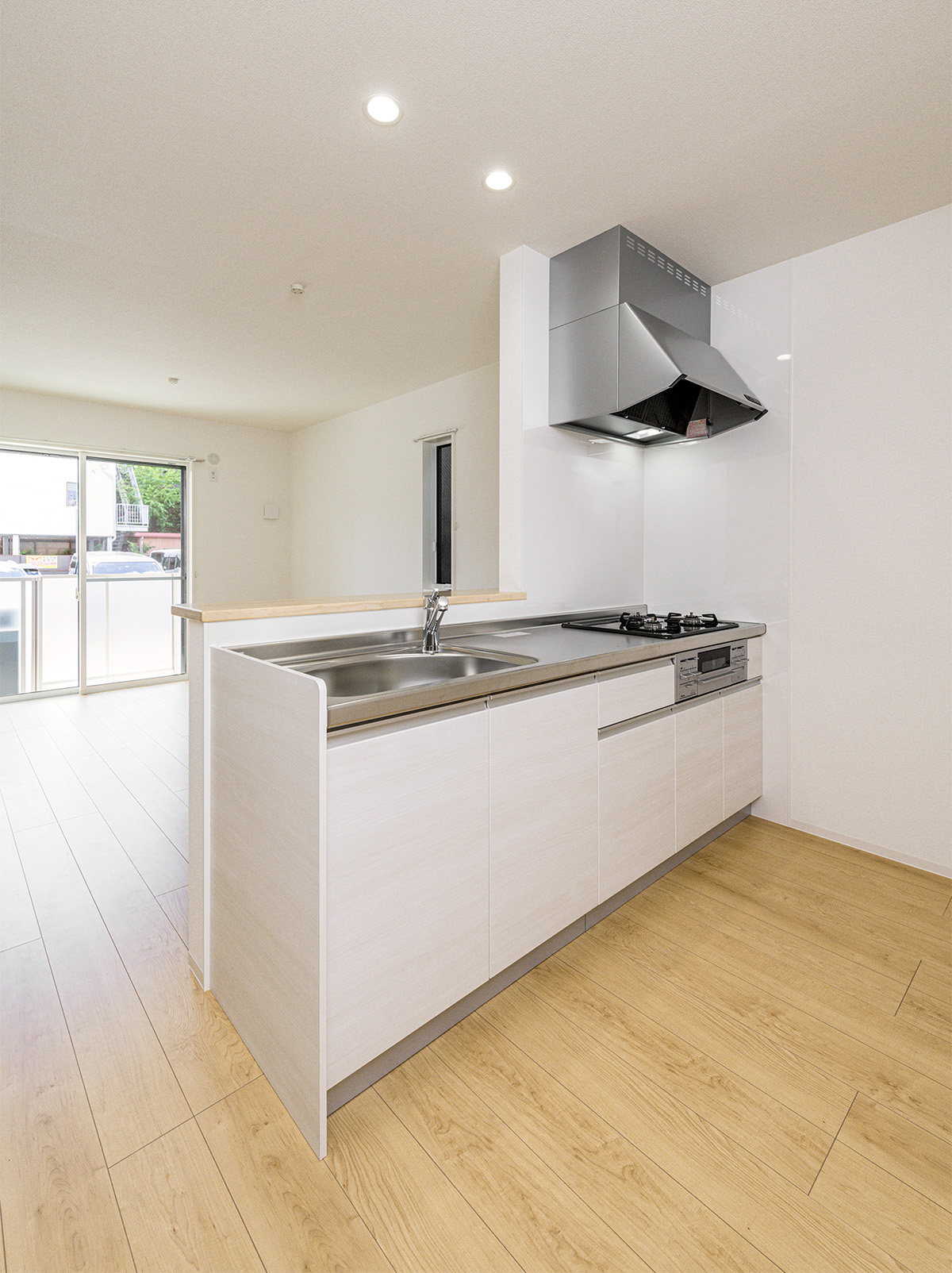 約40坪の土地のファミリー向けメゾネットアパートの3口コンロとグリルを備えた、家事効率を重視したシステムキッチン