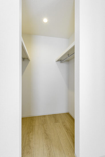 約40坪の土地のファミリー向けメゾネットアパートのハンガーパイプを設置し、収納効率を高めたウォークインクローゼット